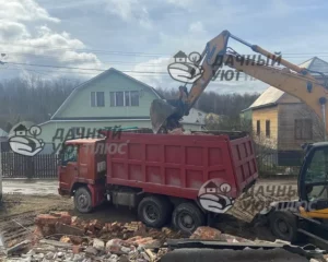 Процесс сноса дома, погрузка мусора экскаватором